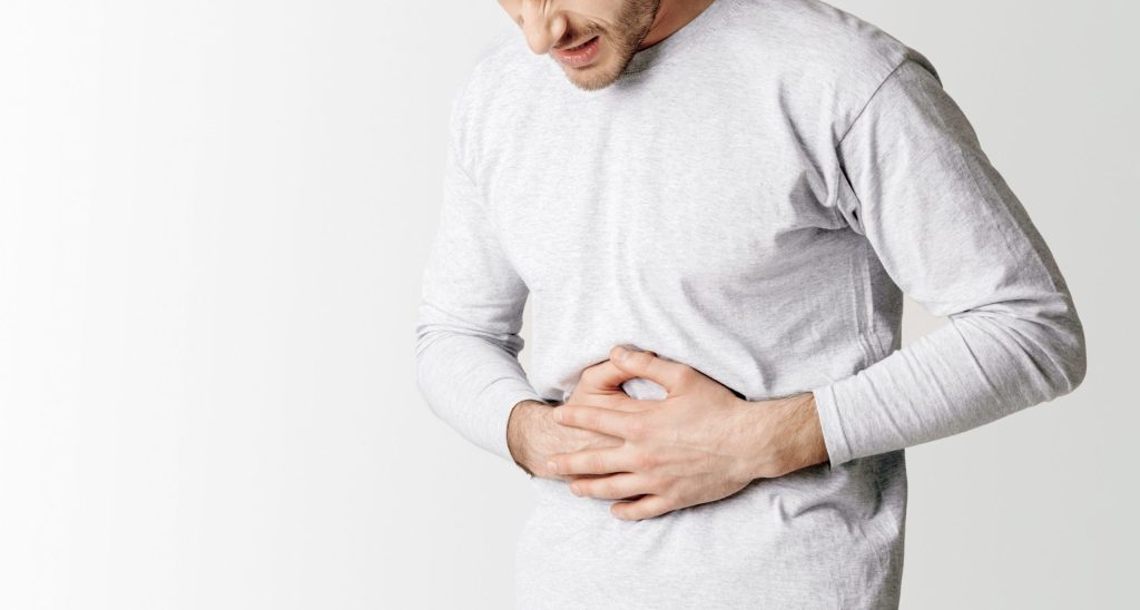 Mann hält sich den Bauch wegen Schmerzen und krümpt sich